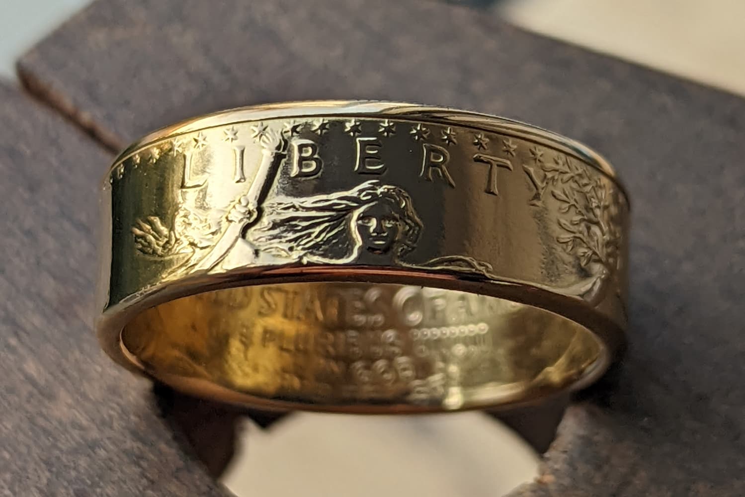 Gold coin ring with embossed text and design on a wooden surface