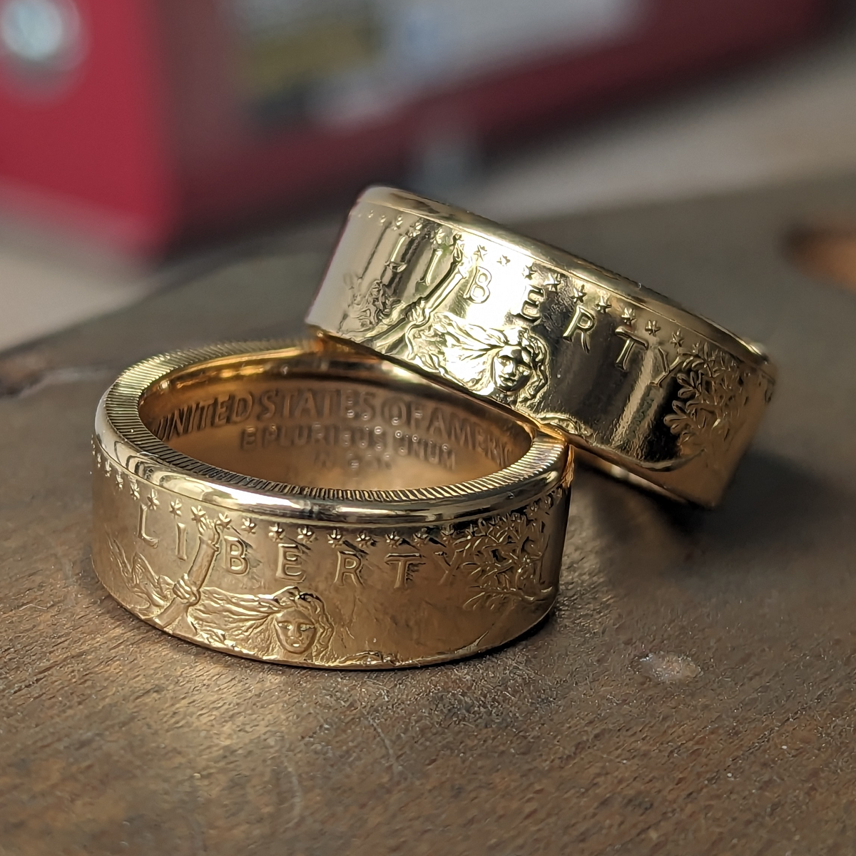 Two American Gold Eagle coin rings on a wooden bench pin
