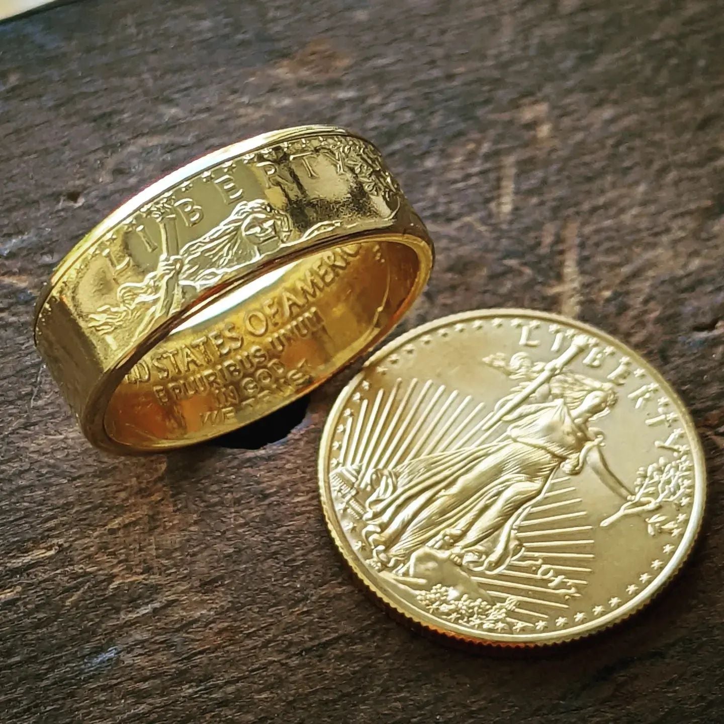 American Gold Eagle coin ring sitting next to a gold coin on a wooden workbench