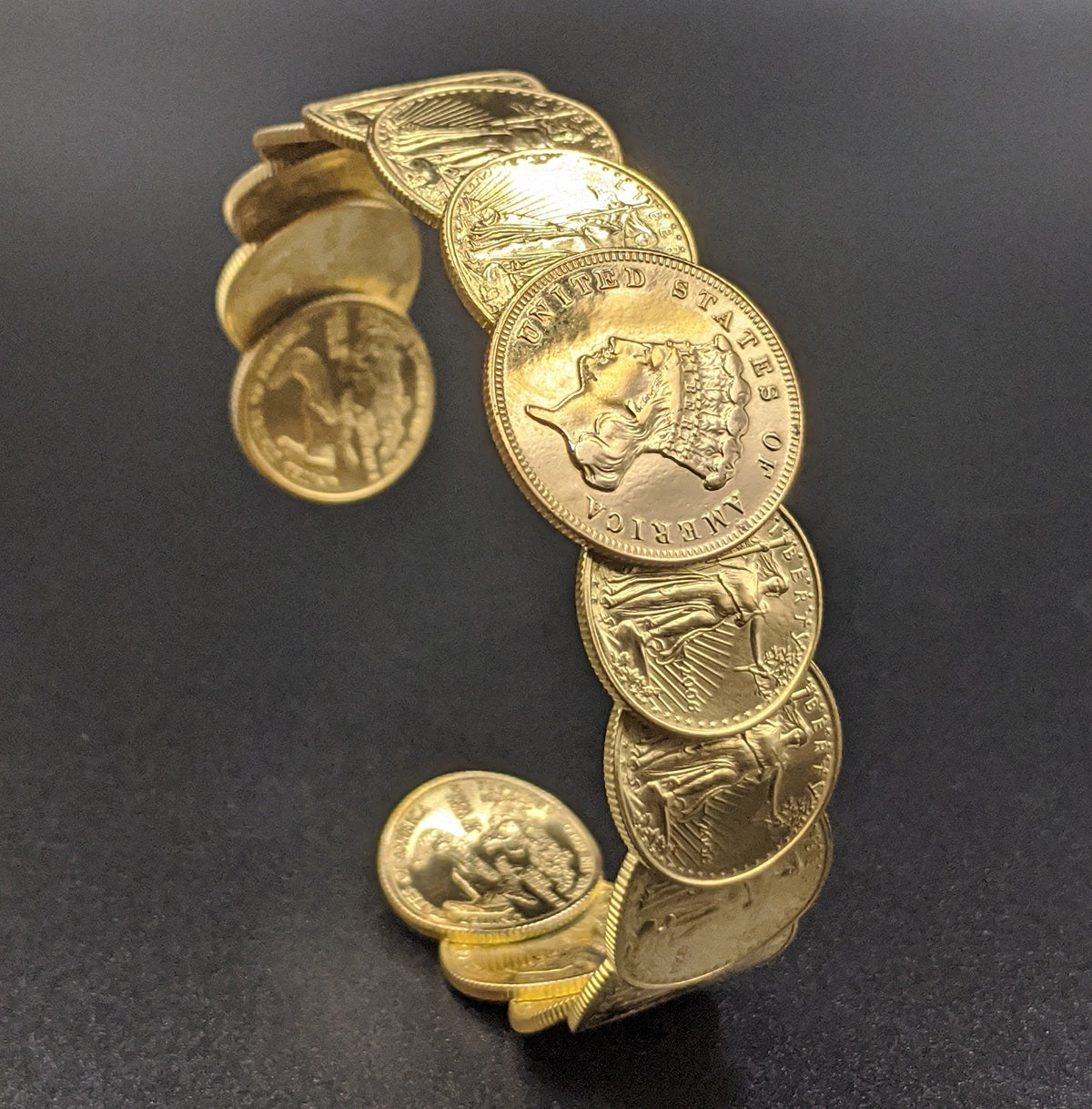 Gold cuff bracelet formed from American gold coins standing on a black background