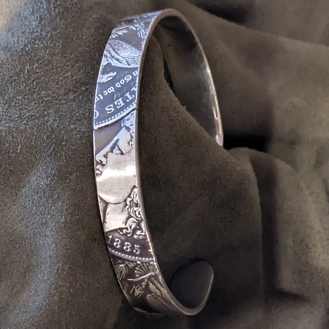 Silver bracelet with engraved design on a brown fabric background