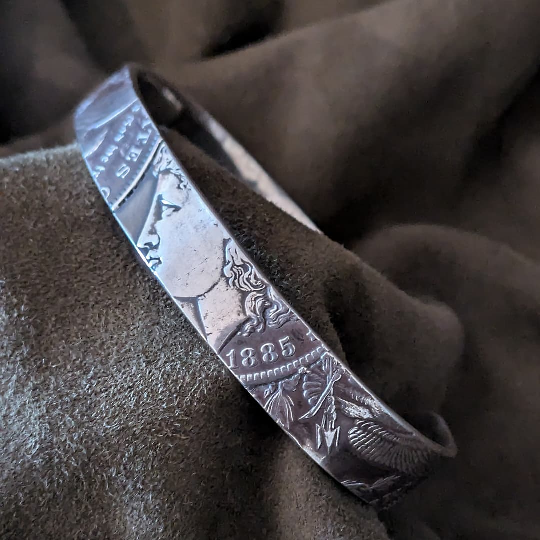 Silver bracelet with engraved design on a brown fabric background