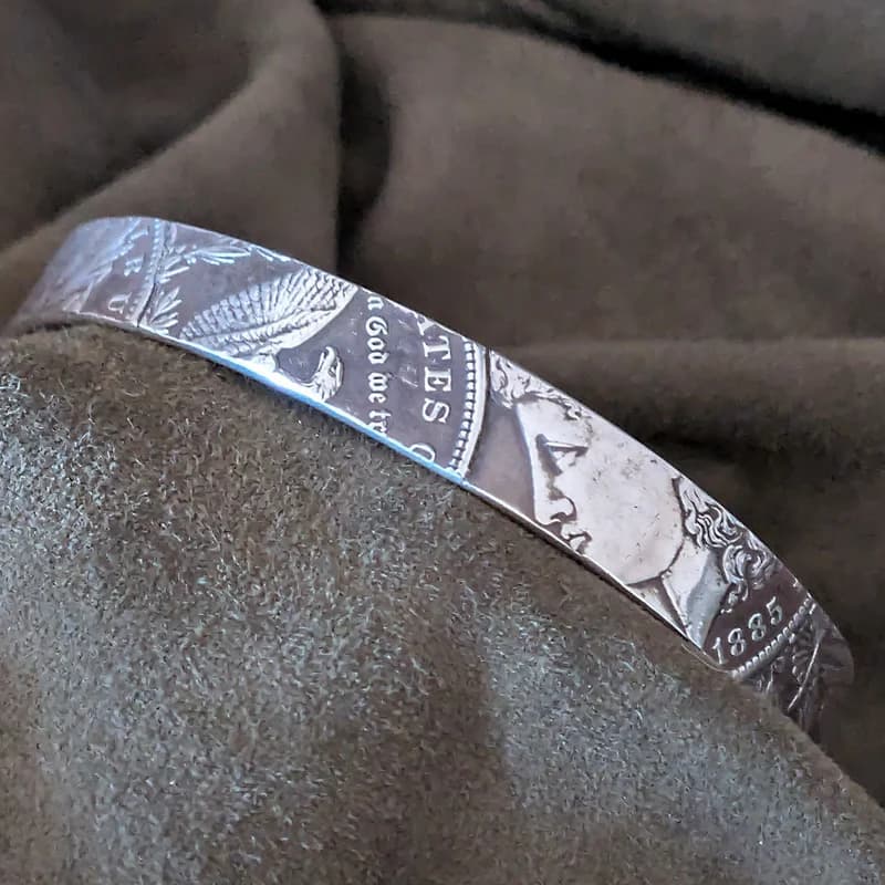 Side view of the Morgan Silver Dollar striped cuff bracelet, brown fabric background.