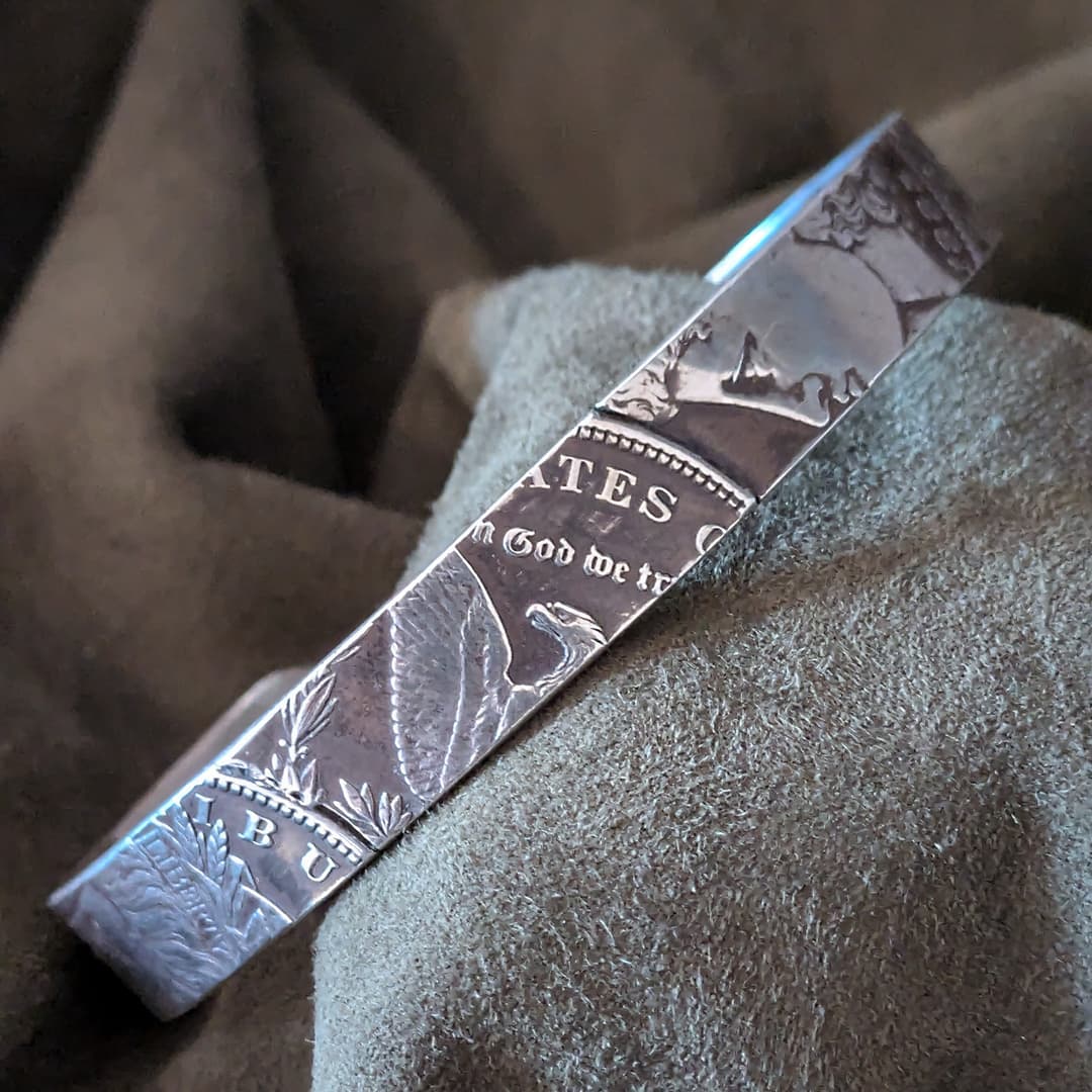 Silver bar with engraved text and design on a textured surface