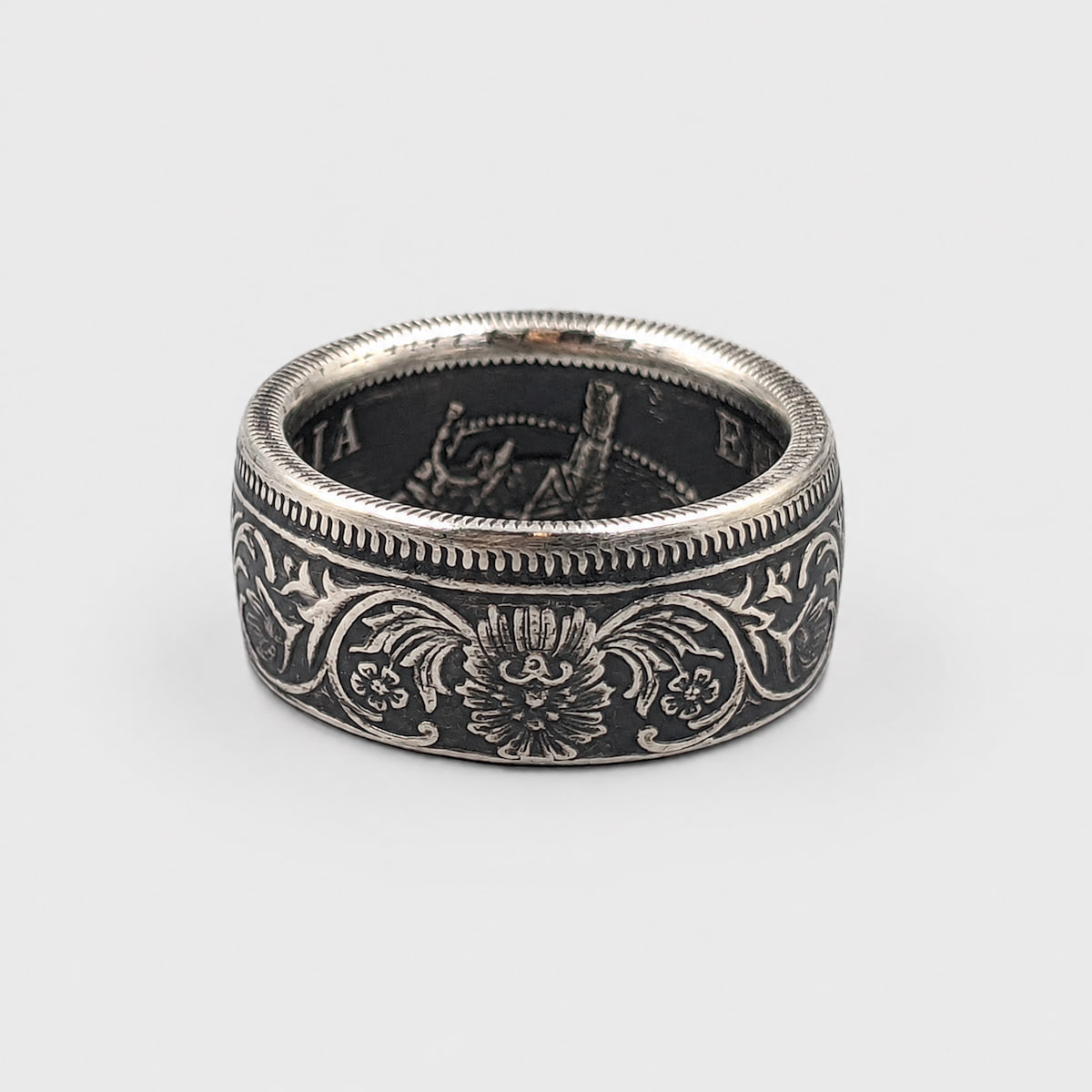 Indian 1 rupee silver coin ring laying flat with a patina finish from Silver State Foundry