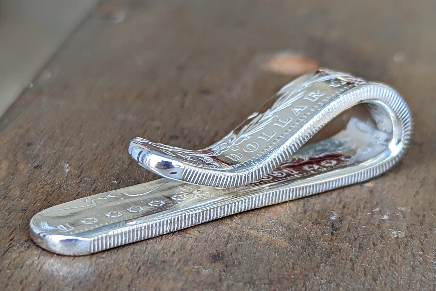 Morgan silver dollar money clip on a wooden bench