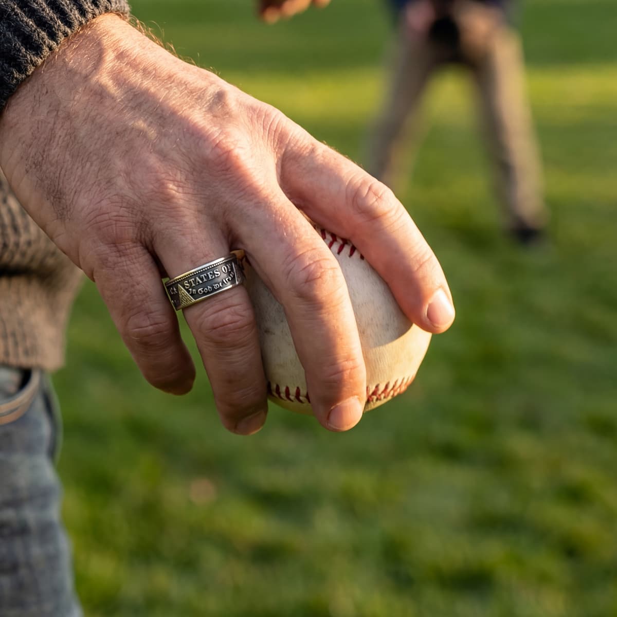Man wearing a Morgan Silver Dollar coin ring with a patina finish and holding a baseball
