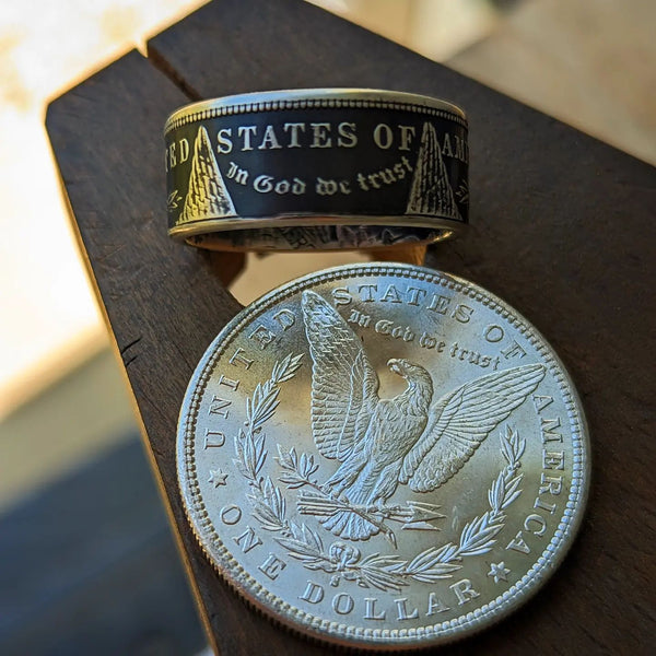 Morgan silver dollar coin ring with a patina finish and a silver dollar resting on a wooden bench pin