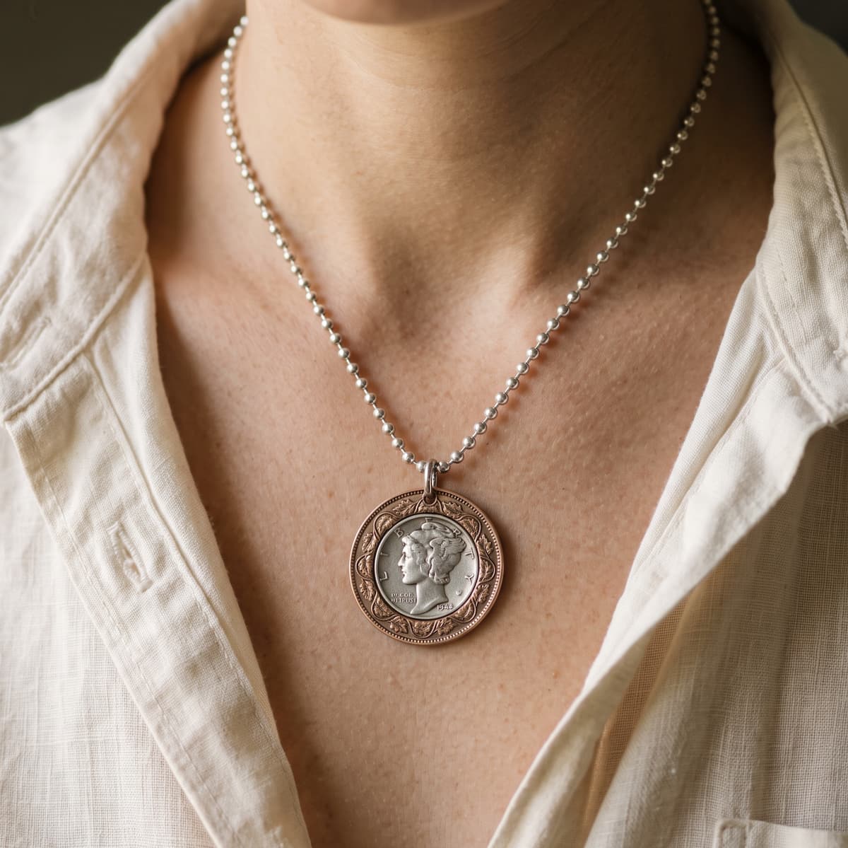 Bullseye pendant on a sterling ball chain worn by a woman with an open collar.