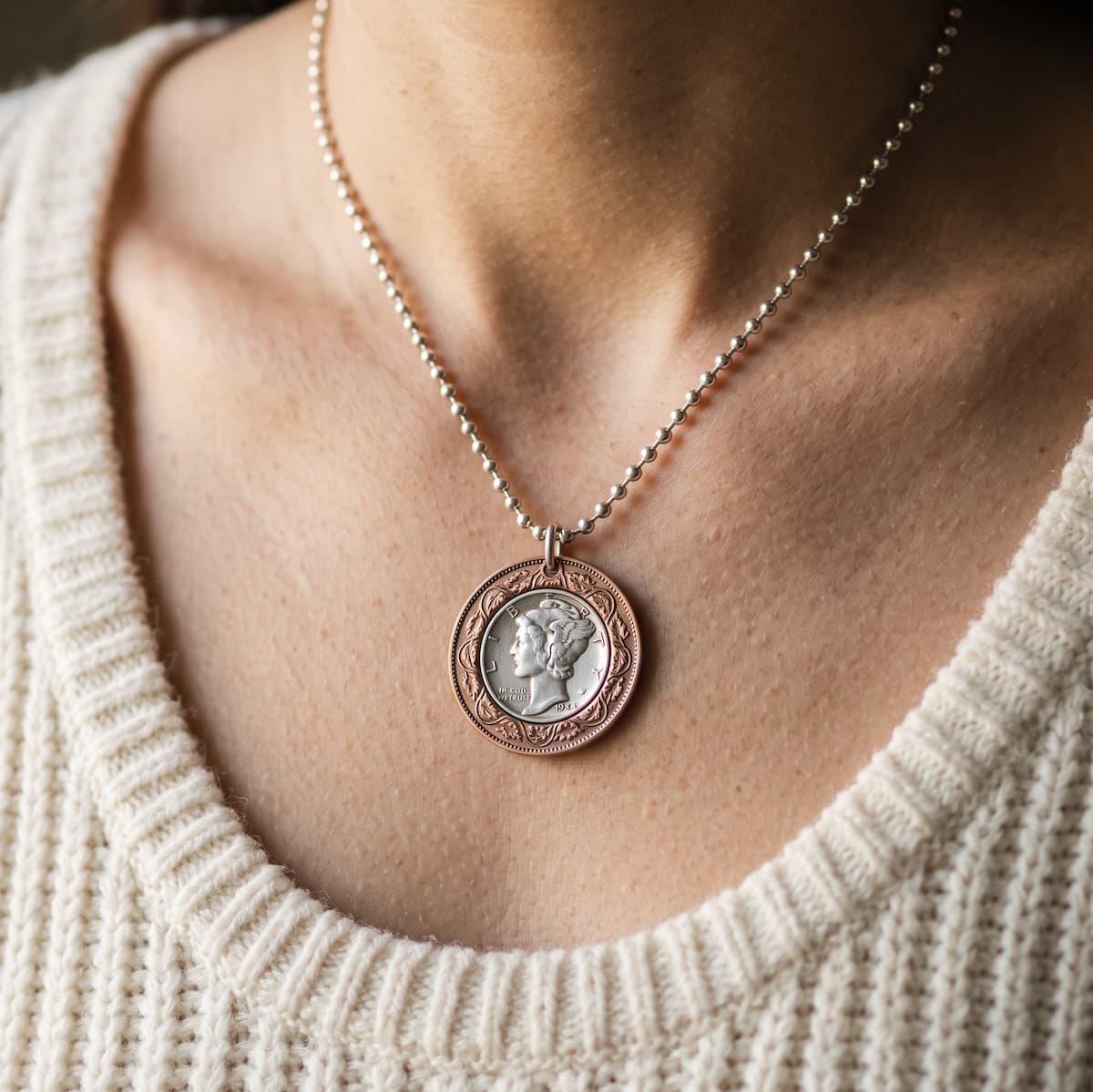 Bullseye pendant on a sterling ball chain worn by a woman in a cream colored sweater.