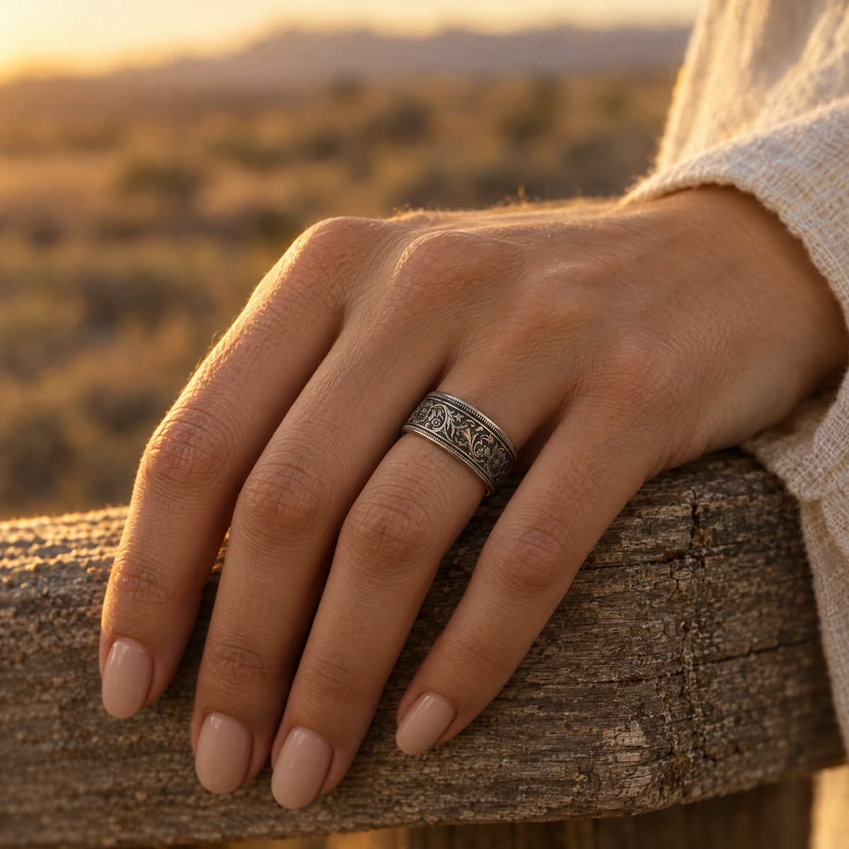 Woman's hand wearing a silver rupee coin ring, resting on a wooden fence