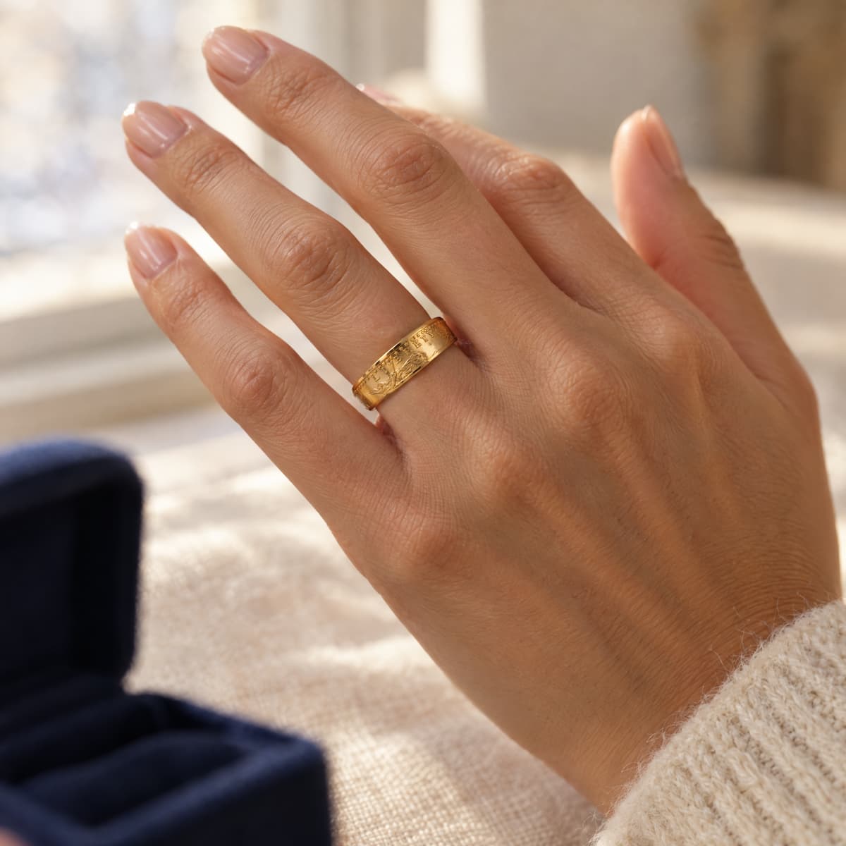 Gold ring on a woman's hand in a warm sunny interior.
